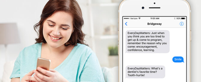 Woman looking at her smartphone, on the screen, there's a text conversation in which someone named "Bridgaway" shares motivational messages.