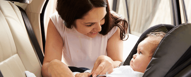 Woman interacting with a baby in a car seat.