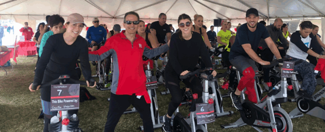 A group of individuals is participating in a spin class under a large tent.