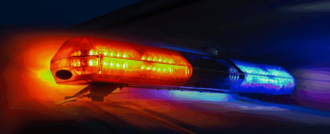 A close-up of a police car light bar with flashing red and blue lights.
