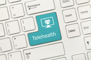 Computer keyboard where one of the keys is highlighted in turquoise, features the word "Telehealth".