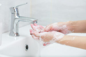 Washing hands with soap under the faucet with water.