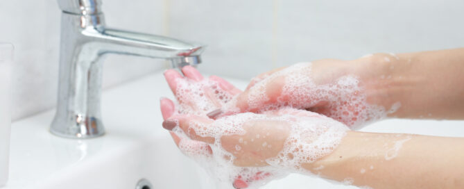 Washing hands with soap under the faucet with water.
