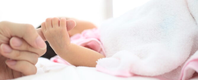 A close-up of a baby's hand gently holding the finger of an adult.