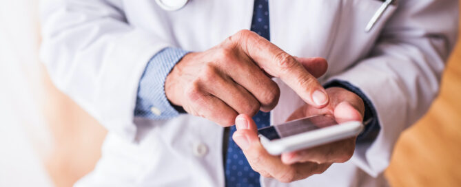 Doctor with smartphone working at the office.