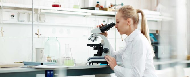 Woman in a laboratory is looking through a microscope.