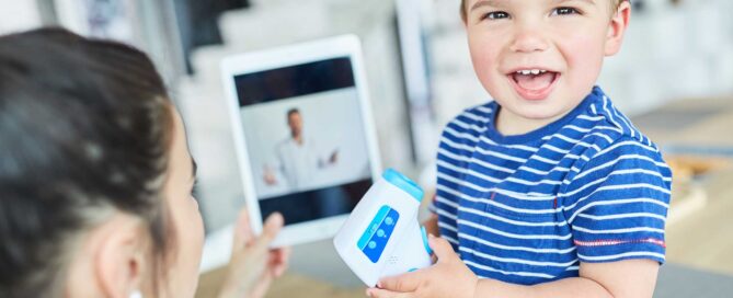 Child holding thermometer being examined by doctor via tablet device.