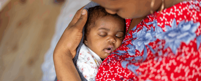 Woman holding a sleeping baby, focusing to their tender moment.