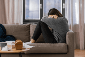 Woman sitting on a couch, appears distressed.