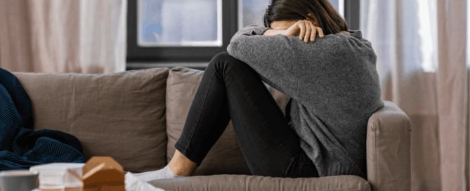 Woman sitting on a couch, appears distressed.