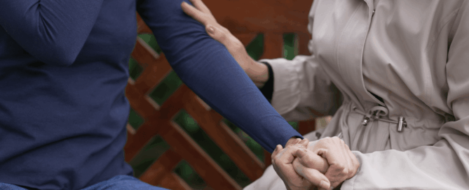 Holding hands while sitting on a park with focus on the hands.