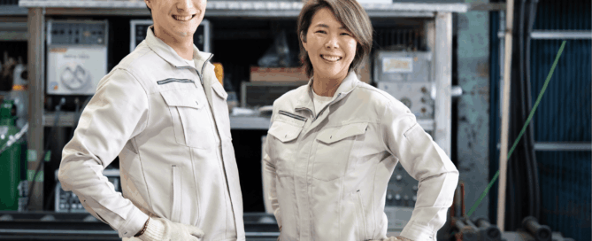 Man and a woman standing side by side on manufacturing environment.