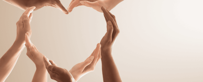 Multiple hands of various skin tones forming a heart shape.