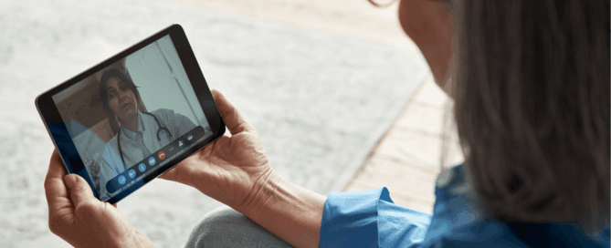 Woman is sitting and using a tablet to engage in a video call with a healthcare professional.
