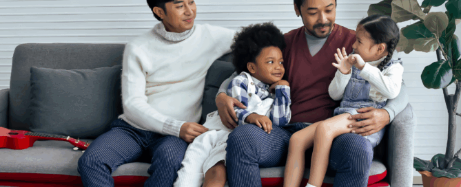 Two adults are seated next to each other, smiling at the two children.