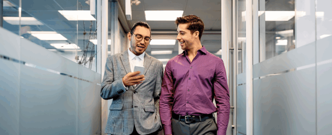 Two men are walking in an office corridor.