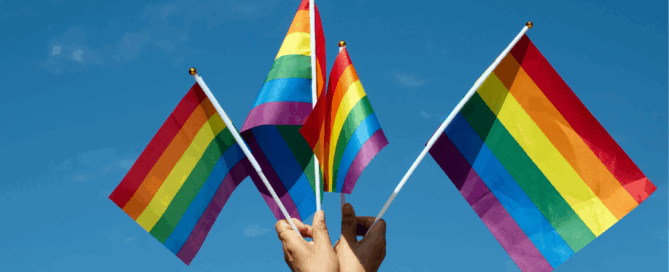 Multiple hands holding a representation of pride movement flags.