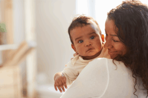 Woman holding a baby close to her chest.