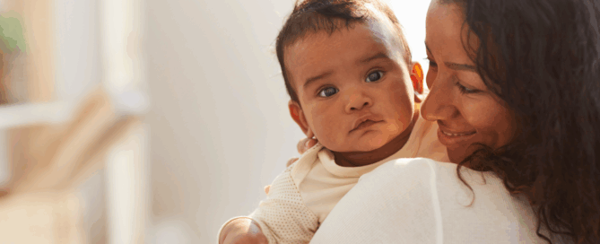 Woman holding a baby close to her chest.