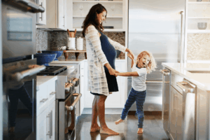 Pregnant woman and a young child are playing together.