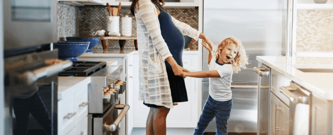 Pregnant woman and a young child are playing together.