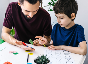 A man and a young boy engaged in a creative activity together.