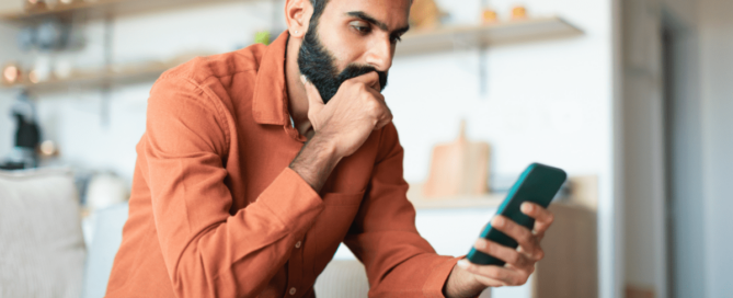 Man sitting on a couch, looking at his phone.