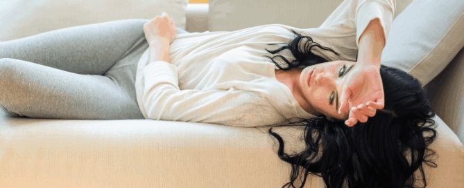 Woman is lying on a sofa.