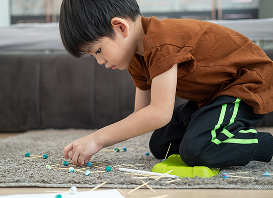 Autism Spectrum Disorder Young boy playing with toys on the floor.