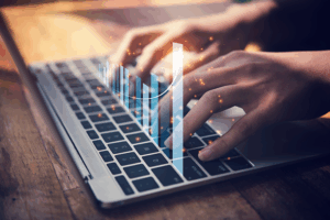 A person's hands typing on a laptop keyboard.