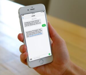 A hand holding a white iPhone, with a message on the screen.