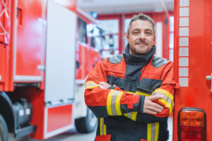 Experienced fire fighter man standing in front of fire truck.