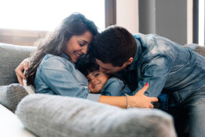 Happy parents and their daughter lying together on a sofa.