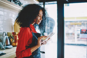 Side view of professional african american waitress in uniform checking order.