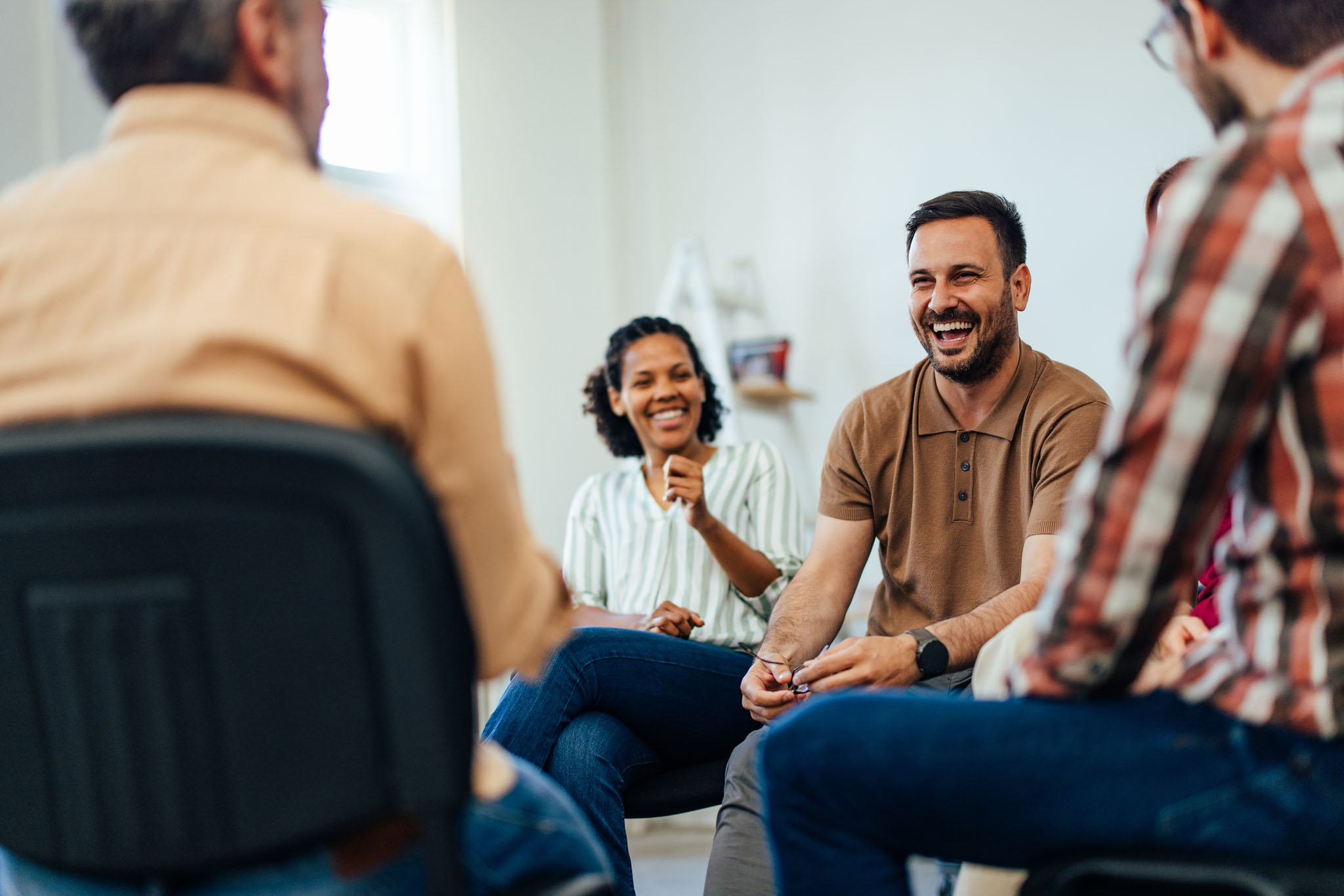 smiling man, talking with people of all ages, during the group therapy.