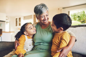 Happy grandmother hugging kids on a sofa.
