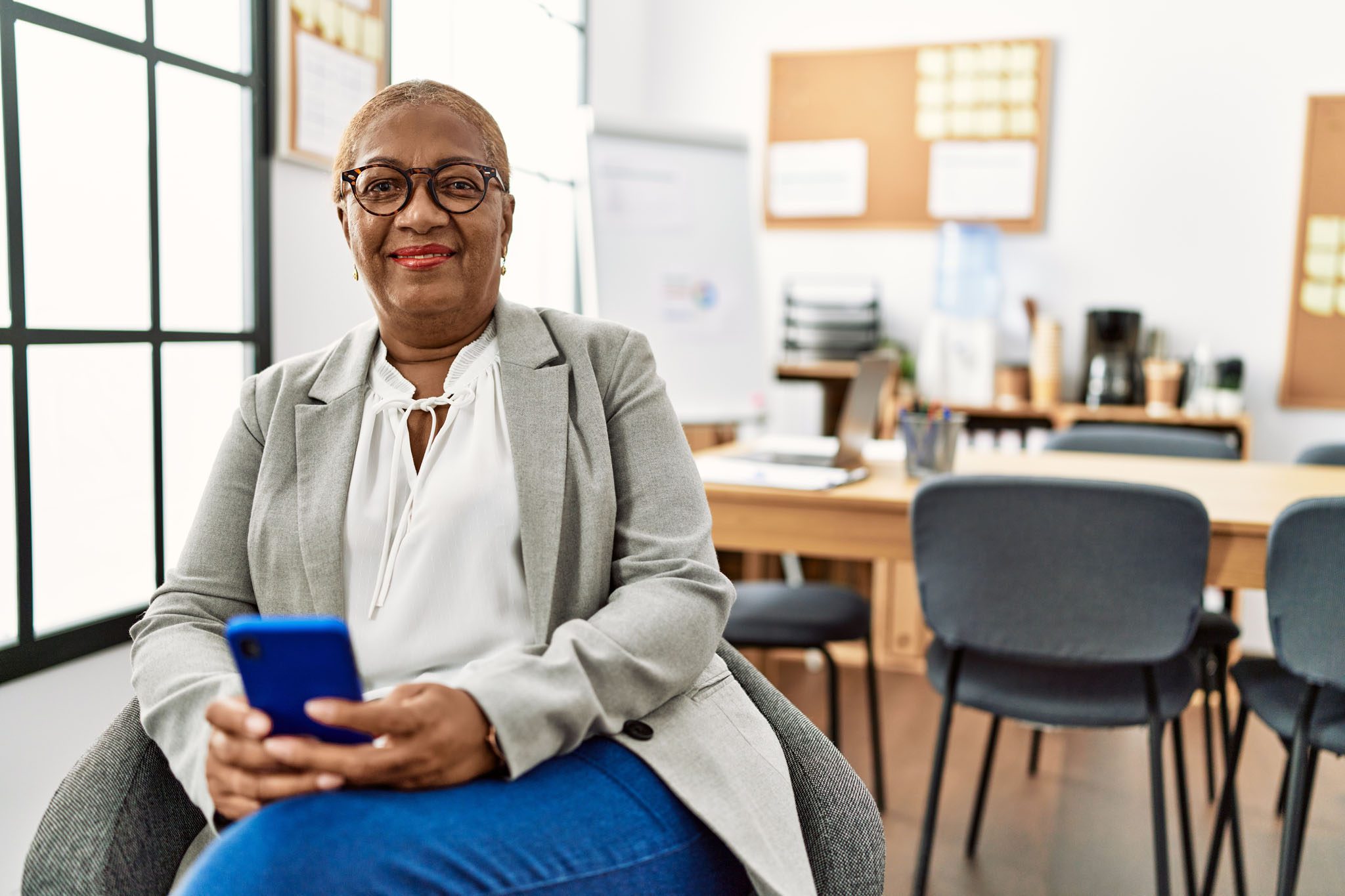 Senior african american woman business worker using smartphone at office