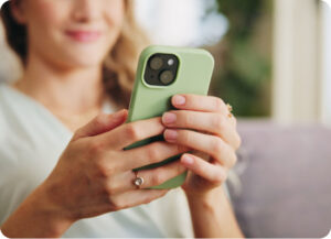 A close-up of a person's hands holding a smartphone with a green case.
