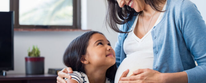 Daughter touching the belly of her pregnant mother