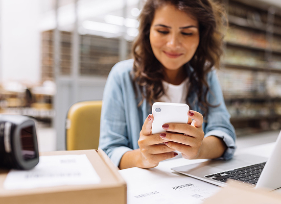 A woman is sitting at a table with boxes and a laptop open in front of her.