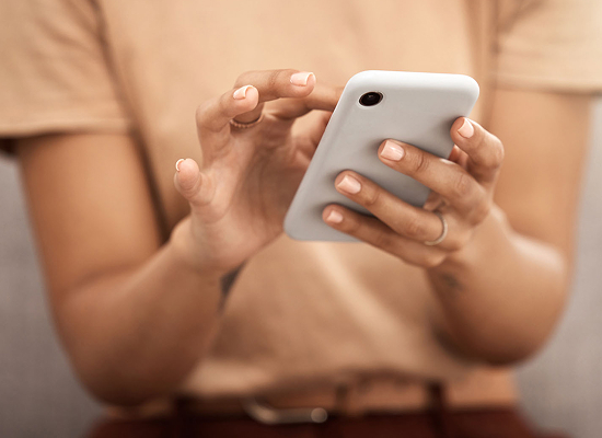 The individual using the phone, with well-groomed nails and wearing rings on their fingers. A close-up of a person's hands holding a smartphone.