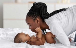 The mother leans toward the baby, making eye contact.